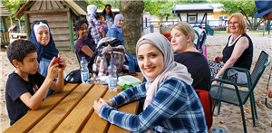 Eine Gruppe von acht Frauen sitzt mit zwei Kindern auf einem Spielplatz in der Essener Gruga zusammen