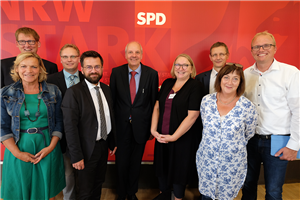 Gruppenfoto mit Vertreter/innen der Caritas in NRW und der SPD-Landtagsfraktion NRW vor einer roten Stellwand der SPD