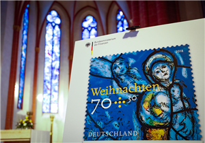Die Weihnachtsmarke 2018, die auf einer Staffelei in der Mainzer Stephanskirche vorgestellt wurde. Das Motiv zeigt ein in blauen Farben gehaltenes Kirchenfenster von Marc Chagall aus dieser Kirche.
