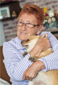 Eine Seniorin, die einen kleinen Hund im Arm hält