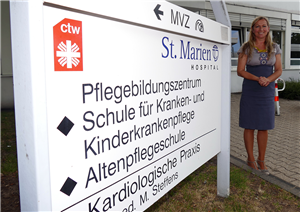 Menka Berres-Förster, die neben dem Eingangsschild des Pflegebildungszentrums am St. Marien-Hospital in Düren steht