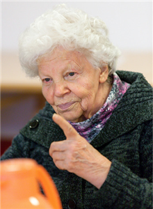 Eine Seniorin, die ihren linken Zeigefinger hebt
