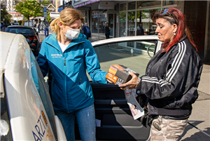 Eine Streetworkerin übergibt in Gelsenkirchen-Horst einer Klientin ein kleines Hilfspaket, was sie aus ihrem Auto herausholt