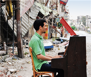 Aeham Ahmad sitzt auf der Straße zwischen den Trümmern der zerstörten syrischen Stadt Yarmouk an einem Klavier und spielt drauf