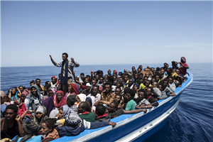 Ein blau-weißes Boot voller Flüchtlinge, dass auf dem Mittelmeer schwimmt