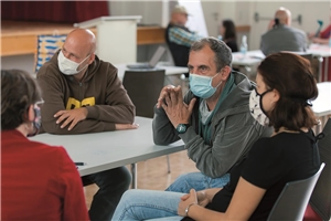 Eine Gruppe aus vier Personen mit Mundschutz sitzen beim 3. Treffen von Menschen mit Armutserfahrung der LAG FW beim Verband IN VIA in Köln an einem Tisch zusammen und reden