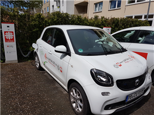 Ein weißes Elektro-Auto des Caritasverbandes Paderborn wird auf einem Parkplatz an einer hauseigenen Ladesäule aufgeladen