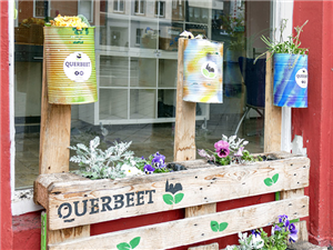 Ein aus einer Palette und drei Konservendosen gebautes Blumenbeet des Projekts 'Querbeet'