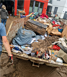 Ein mit Schlamm und zerstörtem Inventar gefüllten Abfallcontainer, der nach der Flutkatastrophe 2021 vor dem Caritas-Haus in Schleiden aufgestellt wurde