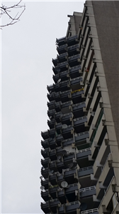  Die Fassade eines schwarz-grauen Plattenbaus in Köln-Chorweiler, mit einer großen Zahl von Balkons, die dicht aneinander liegen