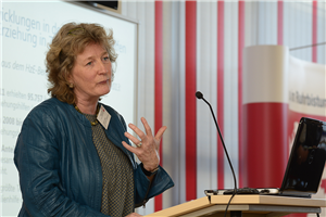 Dr. Monika Weber steht bei der Fachtagung 'Ambulante Hilfen zur Erziehung zwischen Wirksamkeit und Kostendruck' der Caritas in NRW vor einem Pult und hält eine Rede