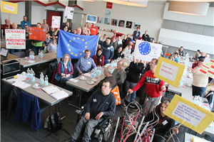 Die Caritas-Werkstatträte in NRW bei ihrem Jahrestreffen am 6. März 2019 in Dülmen in einem großen Tagungsraum. Einige der Teilnehmer halten Schilder, Banner und Fahnen hoch.