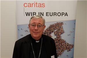 Porträt: Erzbischof Jean-Claude Hollerich, der auf dem CiNW-Europaforum vor einem Roll-up steht