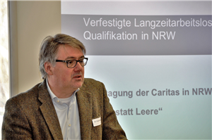 Dr. Frank Bauer hält bei der Fachtagung 'Lehre statt Leere - Chance Berufsabschluss!' in Paderborn seine Präsentation. Im Hintergrund ist seine Power-Point-Präsentation auf der Leinwand zu sehen