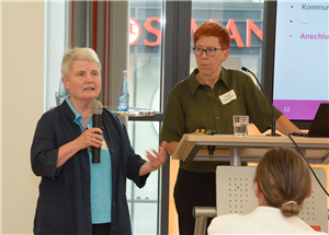 Sr. Dr. Anette Chmielorz und Helga Notteboom stehen bei der CiNW-Fachtagung zur Umsetzung des Pflegeberufegesetzes in Essen an einem Pult und halten einen Vortrag