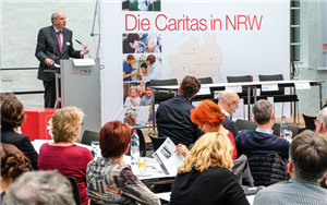 Direktor Heinz-Josef Kessmann steht bei der CiNW-Fachtagung 'Vergaberecht' an einem Pult und hält eine Rede. Im Vordergrund ist das Publikum und im Hintergrund das Podium zu sehen.
