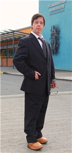 Olaf Keller steht vor der St. Laurentius-Werkstätte in Hagen und ist mit einem Anzug bekleidet