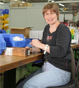 Petra Asch sitzt an ihrem Arbeitsplatz in der in der St. Laurentius-Werkstätte in Hagen und packt Kleinteile in Plastikbeutel