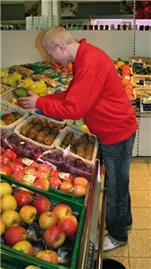Ein Verkäufer prüft eine Mango in der Obst- und Gemüseabteilung