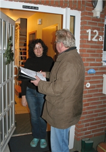 Ein Caritas-Spendensammler steht mit seinen Unterlagen an der geöffneten Wohnungstür einer Frau und führt mit ihr ein Gespräch