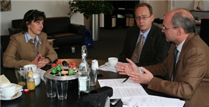 Interviewsituation im Büro der NRW-Gesundheitsministerin mit drei Personen an einem schwarzen, runden Besprechungstisch