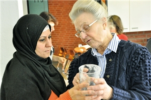 Eine Mitarbeiterin der Caritas-Konferenzen erklärt einer Teilnehmerin etwas zu einem Glasgefäß.