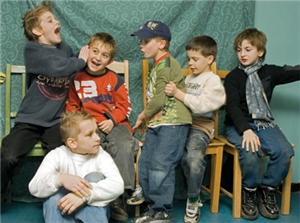 Fünf Jungen sitzen auf Stühlen und albern miteinandern rum. Ein Junge sitzt davor auf dem Boden.