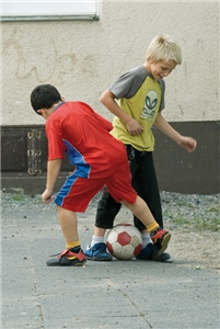 Zwei Jungen spielen Fußball auf einem Vorhof