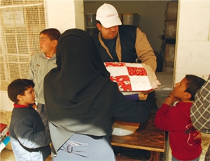 Ein Caritas-Helfer verteilt Decken und Hygiene-Artikel an eine Flüchtlingsfamilie