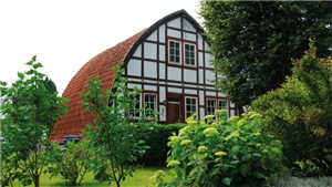 Ein Fachwerkhaus, von den Einwohner des Dorfes Helmern aucht, mit einer Hecke sowie einigen Sträuchern und Bäumen davor Eierhaus genann