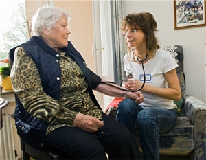 Eine Pflegekraft misst bei einer Bewohnerin eines Altenheims den Blutdruck