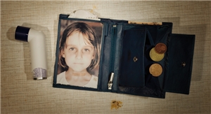 Fotomotiv der Caritas-Jahreskampagne 2012: Schwarze Geldbörse mit dem Bild eines Kindes und ein wenig Kleingeld. Links neben der Geldbörse liegt ein schwarz-weißes Asthmaspray.