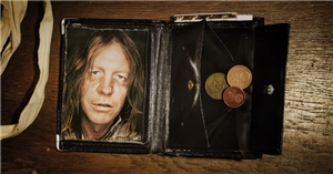 Fotomotiv der Caritas-Jahreskampagne 2012: Schwarze Geldbörse mit dem Bild eines Suchtkranken und ein wenig Kleingeld. Links neben der Geldbörse sind die Henkel eines hellen Stoffbeutels zu sehen.