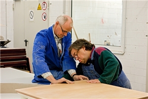 Zwei Männer bei der Arbeit in einer Schreinerei einer Werkstatt für Menschen mit Behinderung