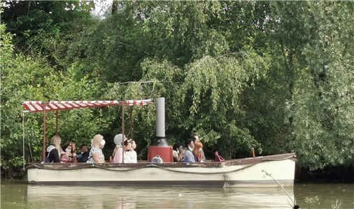 Kinder und Erwachsene sitzen auf einem Ausflugsboot auf einem See.