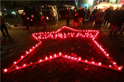 Stern mit Caritas-Schriftzug auf denen rote Kerzen-Lichter stehen.