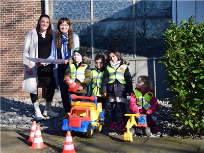 Zwei Frauen stehen mit Bauplänen zusammen mit vier Kindergartenkindern und Spielzeugfahrzeugen vor der außer Dienst gestellten Kirche Heilig Geist in Oberhausen.