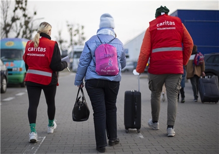 Ukrainische Flüchtlinge mit Gepäck in Polen mit Helfern der polnischen Caritas.