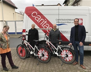 Zwei neue E-Bikes werden von Caritas-Mitarbeitenden in Empfang genommen