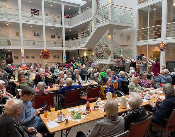 Seniorinnen und Senioren feiern in einem geschmückten Festsaal Fasching