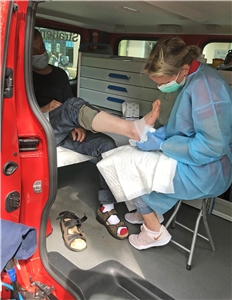 Ambulanz-Krankenschwester legt einem Patienten einen Fußverband an
