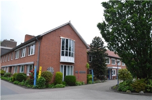 St. Lukas-Heim Stammhaus rotes Backsteingebäude mit Caritas-Flammenkreuz an der Fassade