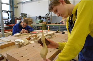 Junger Mann bearbeitet einen kunstvoll gedrechchselten Holzstab mit Schleifpapier