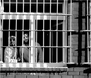 Zwei Häftlinge am vergitterten Fenster