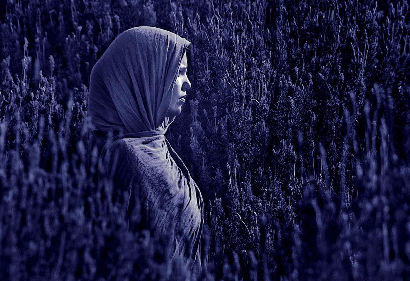 Mädchen mit Kopftuch steht auf einem Feld