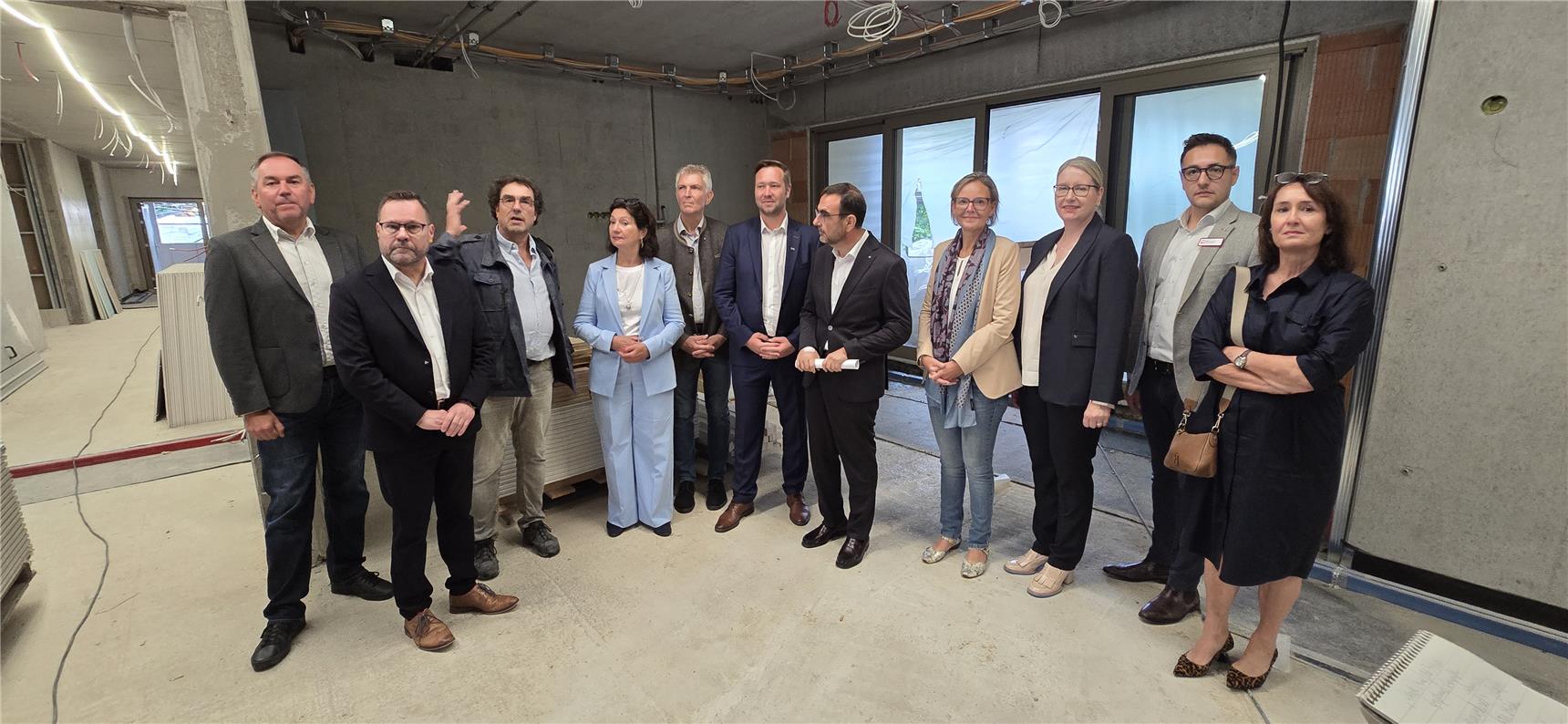 Eine Personengruppe steht im Innenraum eines Rohbaus und schaut sich die Architektur des Gebäudes an.