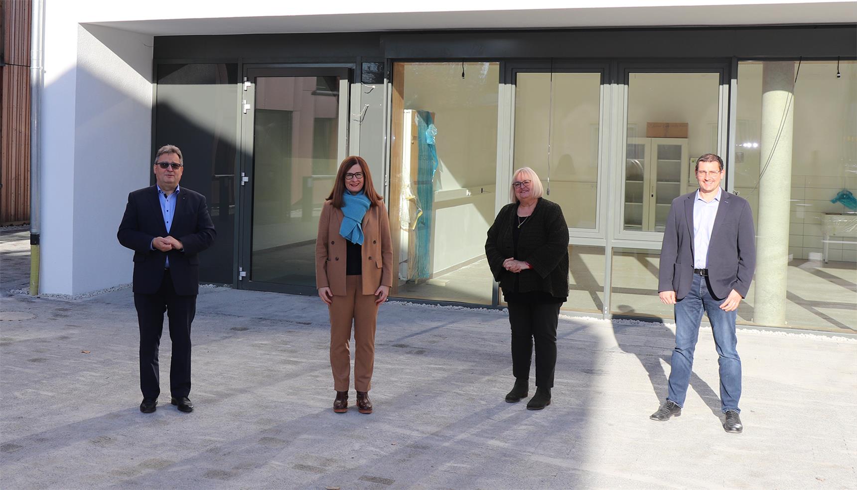 Vier Personen stehen vor einem Neubau Gebäude