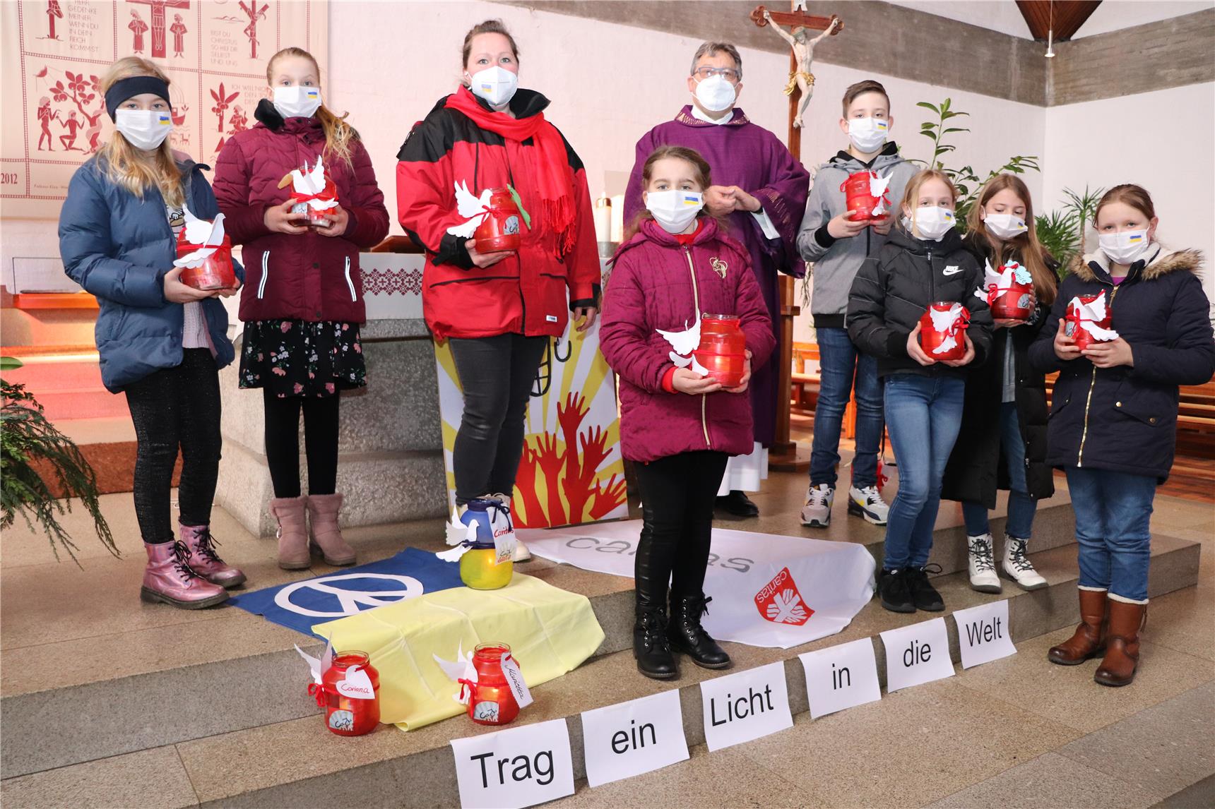 Eine Frau und ein Mann halten das Plakat der Caritassammlung in die Kamera