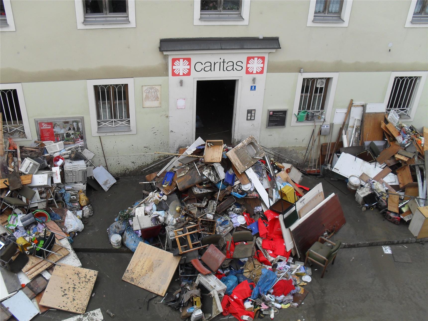 vor einem Caritas-Haus liegen Berge von Möbeln die unbrauchbar sind
