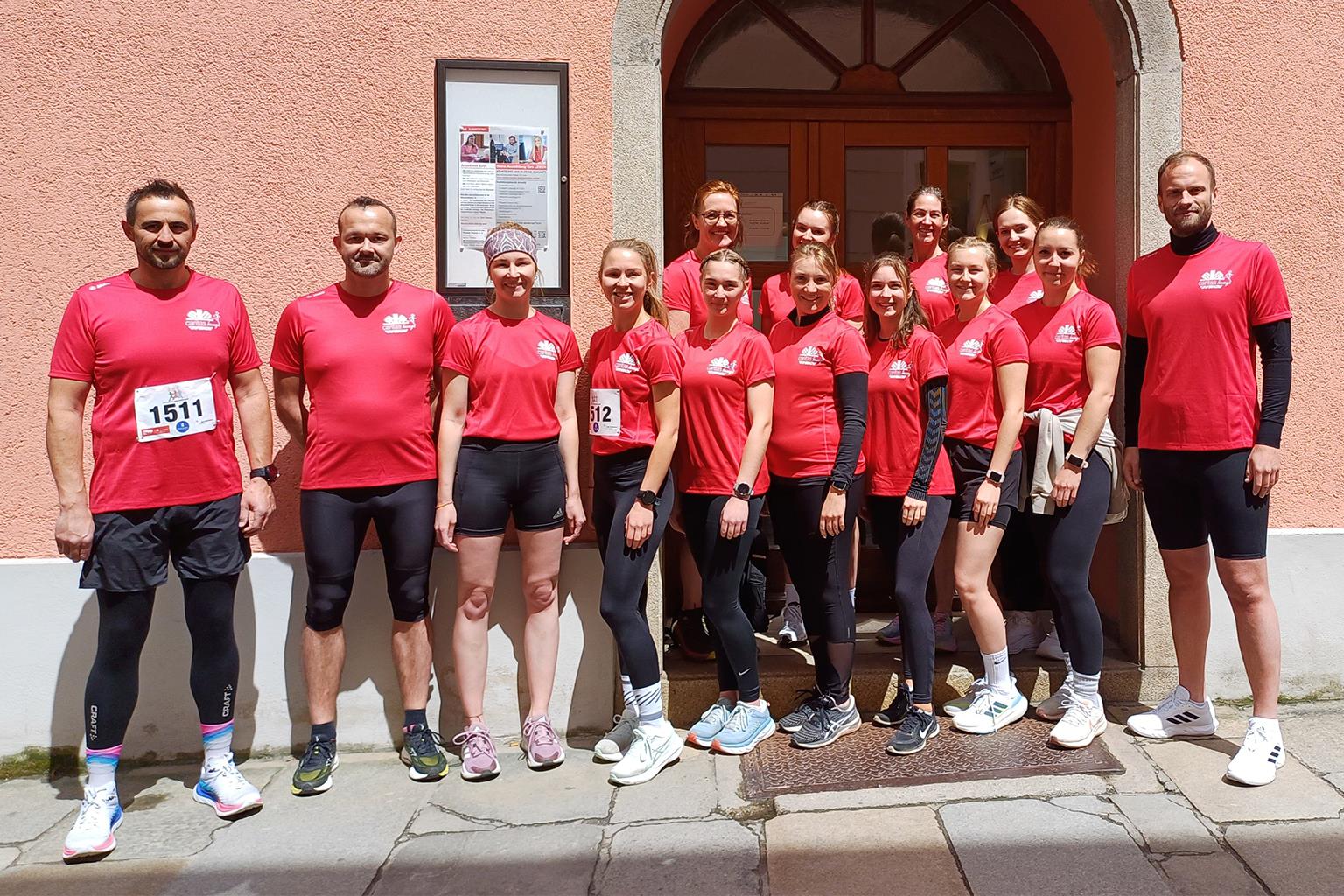 Mehrere Personen stehen vor dem Gebäude der Caritas Passau und lachen in die Kamera.